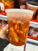  32oz Microwaveable PP Heavy Duty Leak-resistant Translucent Deli Container with lid, holding in front of a supermarket shelf  Kimchi